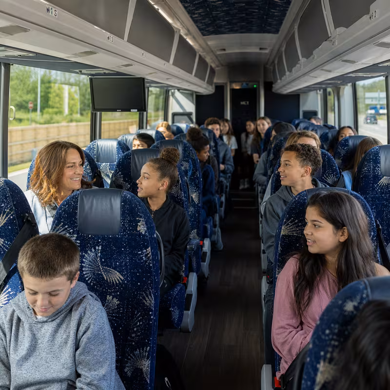 Group boarding a white charter bus for School Transportation transportation in Dallas